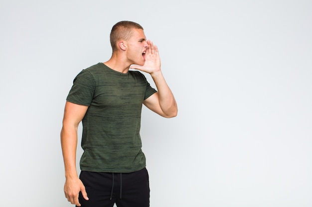 Blonder Mann schreit laut und wütend, um Platz auf der Seite zu kopieren, mit der Hand neben dem Mund