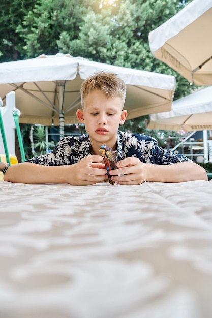 Blonder Schuljunge in bunten Hemdspielen, die am Tisch sitzen und auf Essen warten