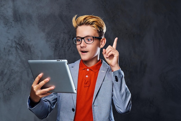 Blonder Schuljunge mit Brille hält Tablet-PC.