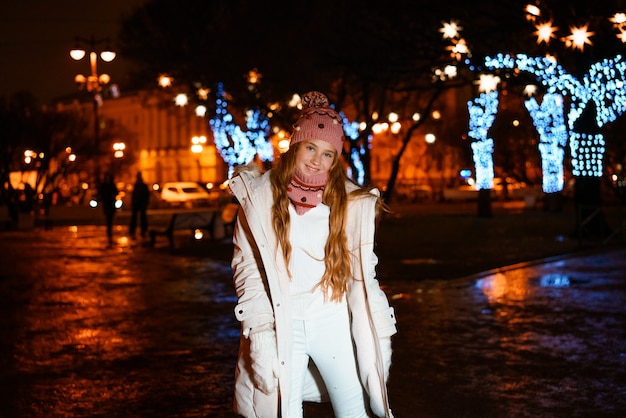 Blonder Teenager mit langen Haaren in Winterkleidung an einem festlichen Winterabend auf Straßennahaufnahmeportrai...