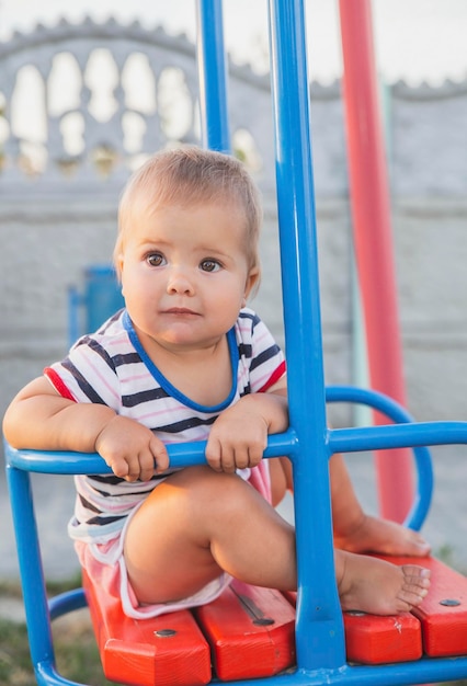 Blondes Baby auf einer Schaukel bei Sonnenuntergang