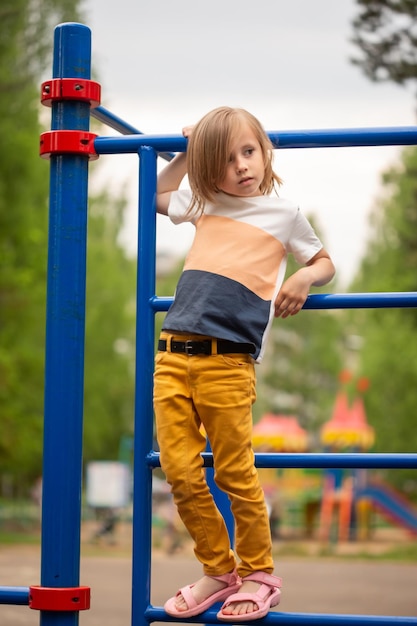 Blondes charmantes kaukasisches Mädchen in lässigem Abschluss, das im Sommer auf dem Spielplatz spielt