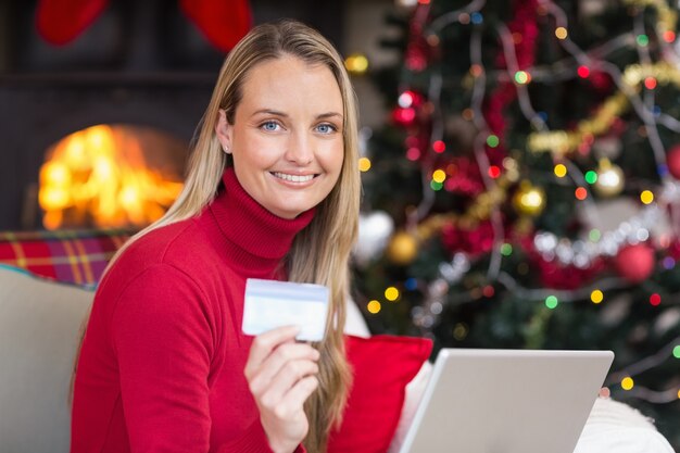 Blondes Einkaufen online mit Laptop am Weihnachten