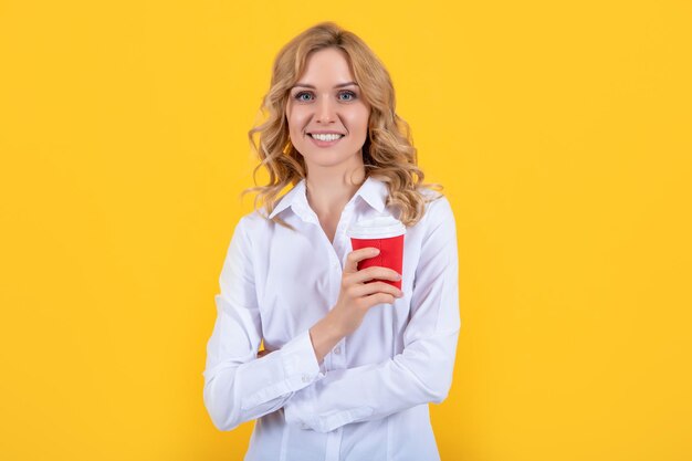 Blondes Frauenlächeln mit Kaffeetasse auf gelbem Hintergrund