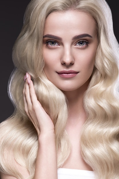 Blondes Haar-Frauen-schöne gelockte Frisur gewelltes langes Haar natürlich bilden. Studioaufnahme. Auf schwarz