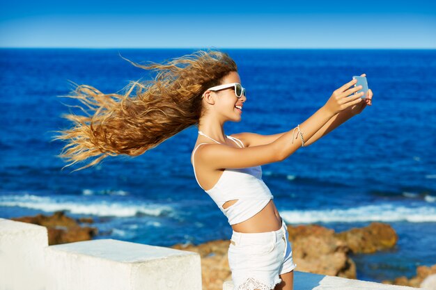 Blondes jugendlich Mädchen-Foto selfie auf Smartphone am Strand