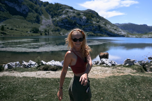 Foto blondes kaukasisches mädchen mit sonnenbrille, zahnspange an den zähnen, das an der kamera am see spaß hat