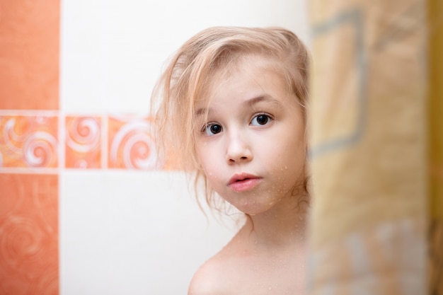 Blondes Kind im Badezimmer unter der Dusche.