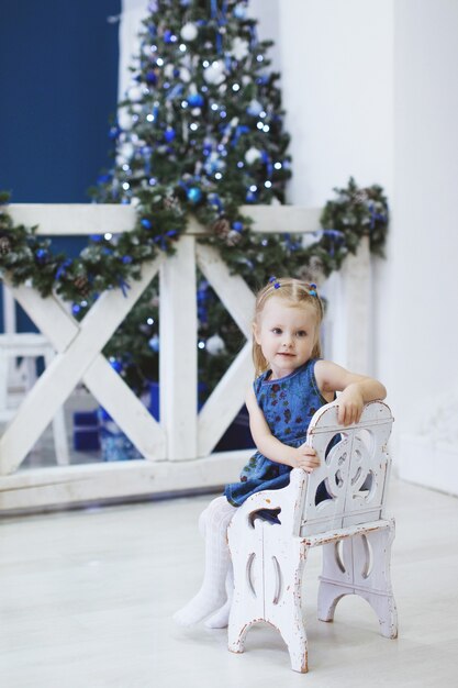 Blondes Kind mit Weihnachtsbaum. Luxuriöse Weihnachtsdekoration.