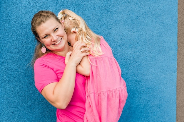 Blondes kleines Mädchen mit Cochlea-Implantat, das mit seiner Mutter im Freien spielt Hörbehinderung, Taubheit und Gesundheitskonzept Behinderung und Inklusion