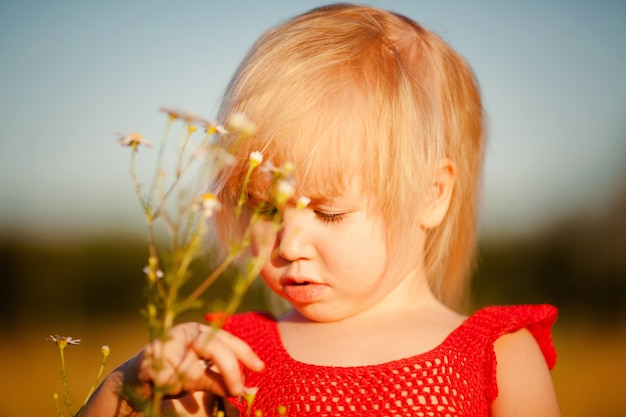 Blondes Mädchen auf dem Gebiet mit Blumen