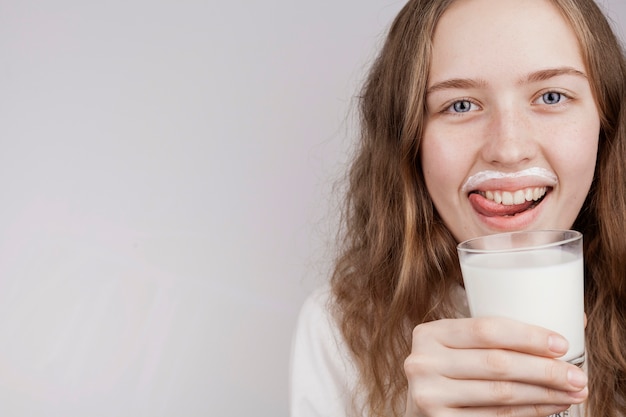 Foto blondes mädchen, das ein glas milch mit kopienraum hält