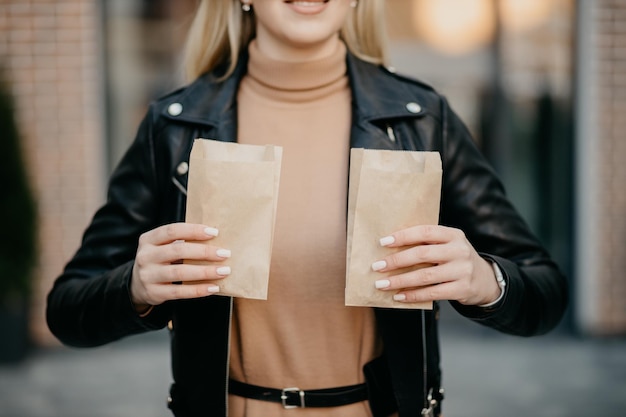 Blondes Mädchen, das ein Paket von Croissants auf dem Hintergrund des Einkaufszentrums hält Schönes Mädchen im Stadtzentrum Croissant in einem Paket