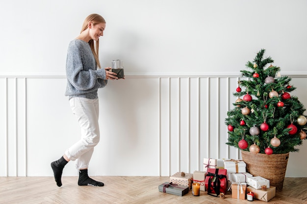 Blondes Mädchen, das einen Weihnachtsbaum mit Geschenken schmückt