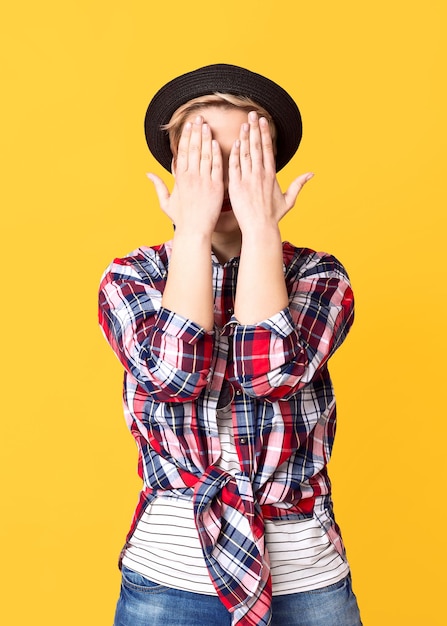 Blondes Mädchen des Hipsters verbirgt ihr Gesicht mit den Händen. Verstecken, lustiges Konzept