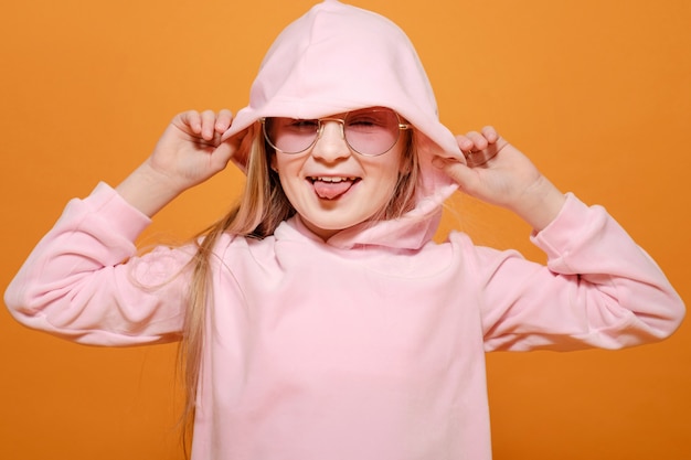 Blondes Mädchen des Modemodells mit Brille in den rosa Kleidern auf Gelb