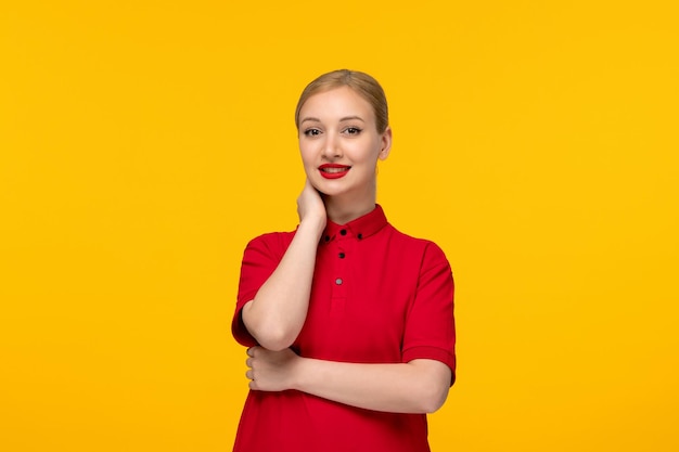 Blondes Mädchen des roten Hemdtages, das in einem roten Hemd auf einem gelben Hintergrund lächelt