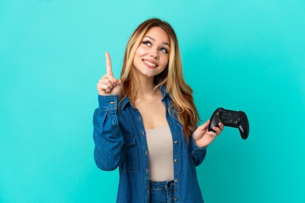 Blondes Mädchen des Teenagers, das mit einem Videospielcontroller über einer isolierten Wand spielt und auf eine großartige Idee hinweist