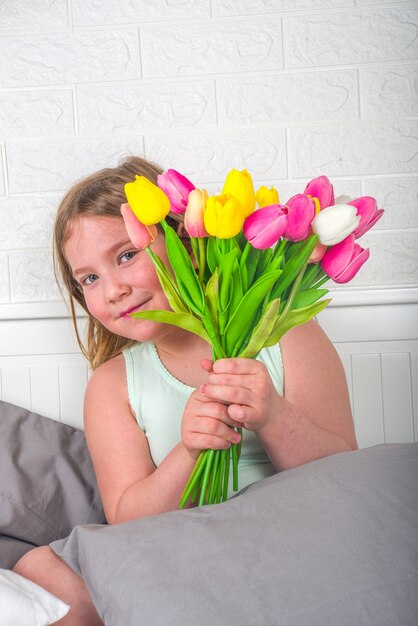 Blondes Mädchen des Vorschulkindkindes mit einem Blumenstrauß von Tulpenblumen, Kopienraum