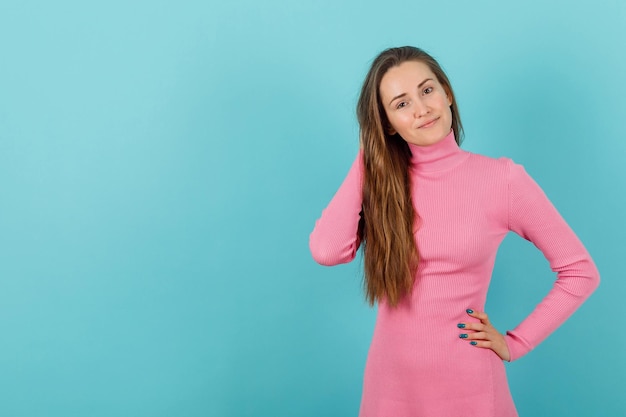 Blondes Mädchen hält eine Hand hinter dem Kopf und die andere an der Taille auf blauem Hintergrund