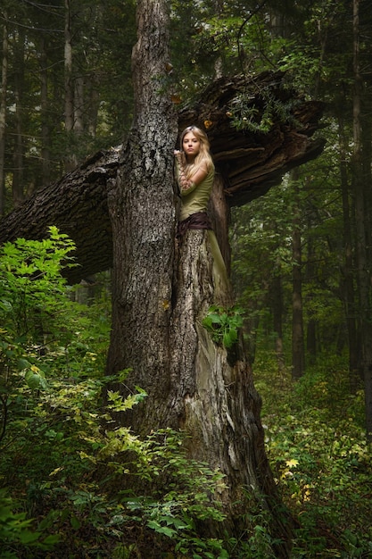 Blondes Mädchen im Kleid spazieren in einem magischen Wald