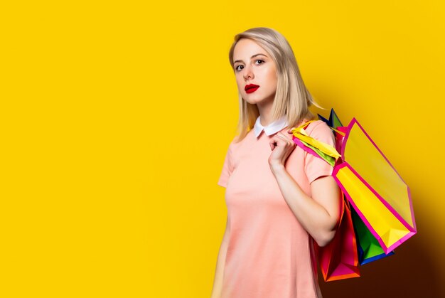 Blondes Mädchen im rosa Kleid mit Einkaufstüten