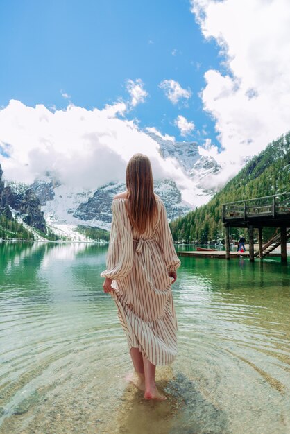 Blondes Mädchen im weißen Kleid geht auf dem Wasser Lago di Braies Dolomites Italy