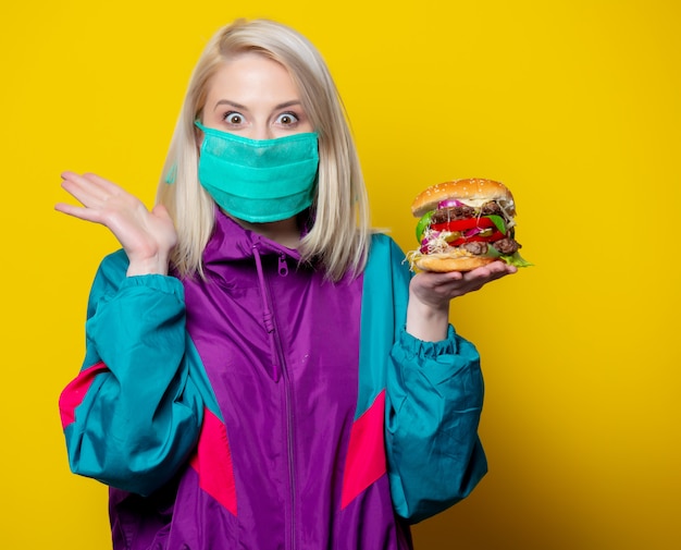 Blondes Mädchen in Gesichtsmaske mit Burger