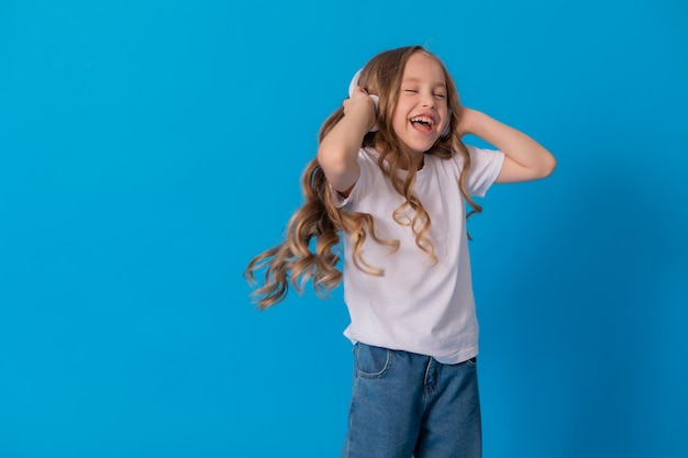 Blondes Mädchen in Jeans und weißem T-Shirt hört Musik mit Kopfhörern und tanzt