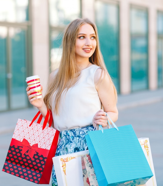 blondes Mädchen, mit Einkaufstüten aus dem Shop zu Fuß.