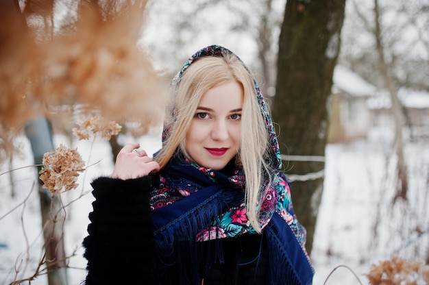 Blondes Mädchen mit Hand gesticktem Schal warf am Wintertag auf.