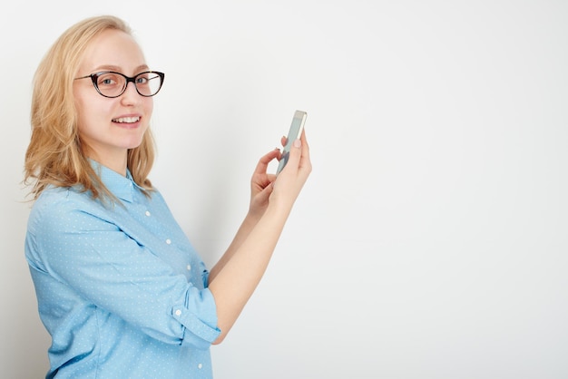 Blondes Mädchen mit Handy auf weißem Hintergrund