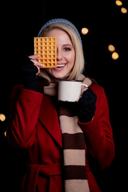 Blondes Mädchen mit Tasse Kaffee und Waffel