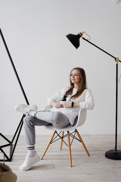 Foto blondes mädchen sitzt auf einem sessel zu hause in der arbeitsatmosphäre, arbeitet von zu hause aus, die freude, zu hause zu sein