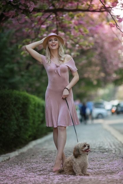 Blondes Modell mit elegantem Hut auf dem Kopf während eines Spaziergangs im Stadtpark