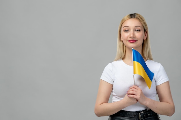 Blondes nettes Mädchen des Ukraine-Russland-Konflikts mit rotem Lippenstift und ukrainischer Flagge lächelnd