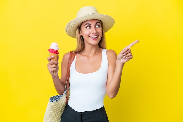 Blondes uruguayisches Mädchen im Sommer, das Eis isoliert auf gelbem Hintergrund hält, um die Lösung zu realisieren, während es einen Finger hochhebt