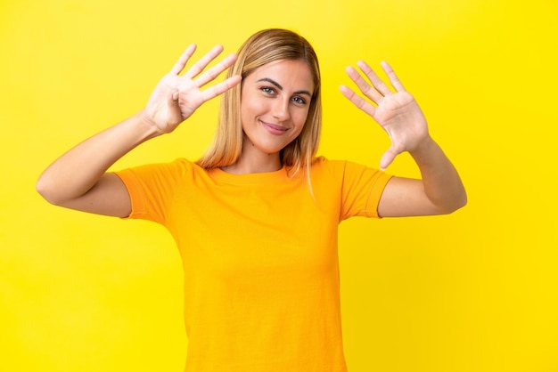 Blondes uruguayisches Mädchen isoliert auf gelbem Hintergrund, das neun mit den Fingern zählt