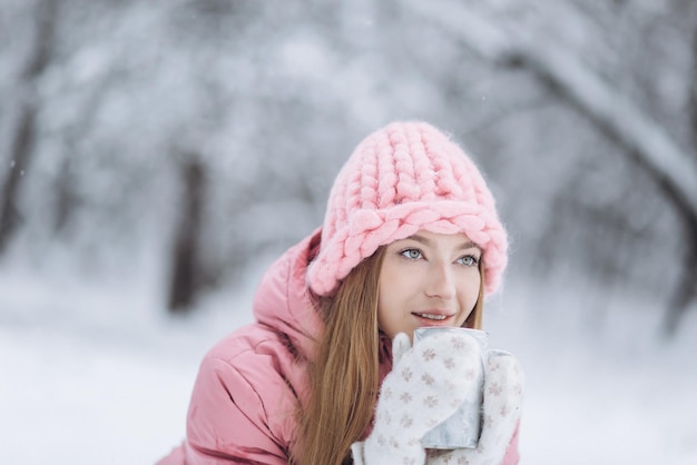 Blondie-Mädchen mit Tasse heißem Tee draußen im Winterpark