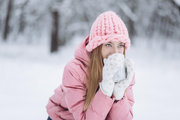 Foto blondie-mädchen mit tasse heißem tee draußen im winterpark