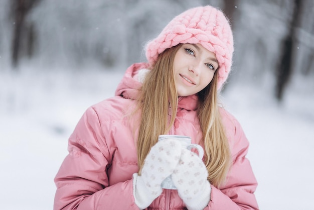 Blondie-Mädchen mit Tasse heißem Tee draußen im Winterpark