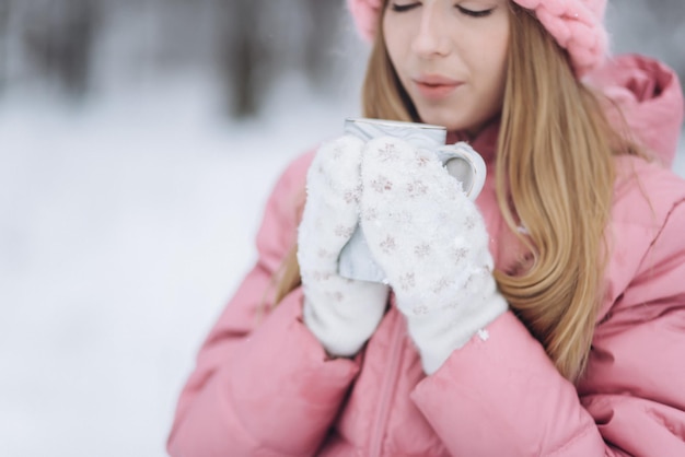 Blondie-Mädchen mit Tasse heißem Tee draußen im Winterpark