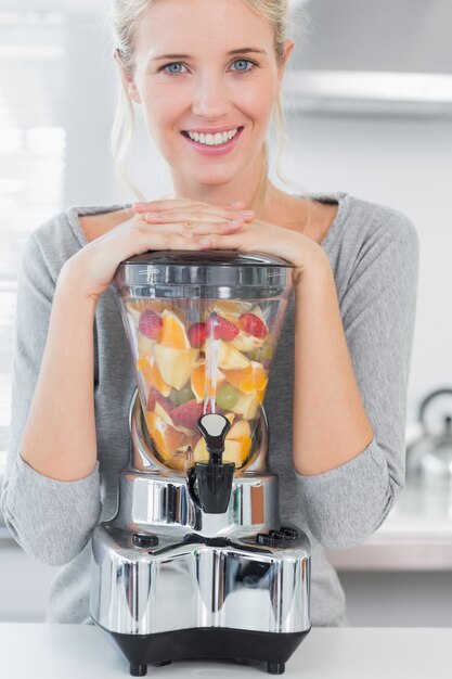 Blondine, die auf ihrem Juicer sich lehnen