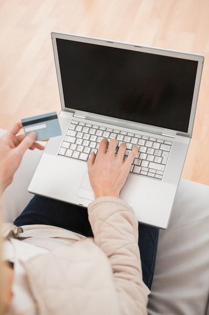 Blondine, die Laptop auf Couch verwenden