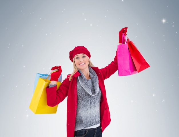 Blondine in der Winterkleidung, die Einkaufstaschen hält