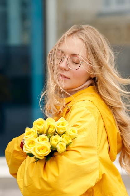 Blondine mit gelben Blüten auf blauem Grund bei einem Spaziergang in der Stadt