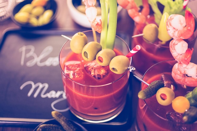 Bloody Mary Cocktail garniert mit Oliven, Gurken und Cocktailgarnelen.