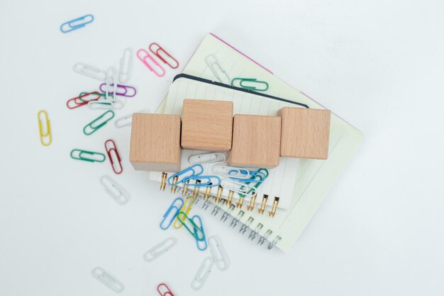 Bloque de cubo de madera vacío en el cuaderno con clips de papel en la mesa blanca signo de objeto de negocio información educación y aprendizaje concepto espacio de copia