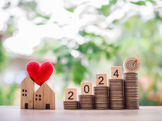 Bloque de madera con 2024 y objetivo icono de negocio casa en miniatura en la pila de monedas el concepto de inversión inmobiliaria Casa hipoteca Real estste