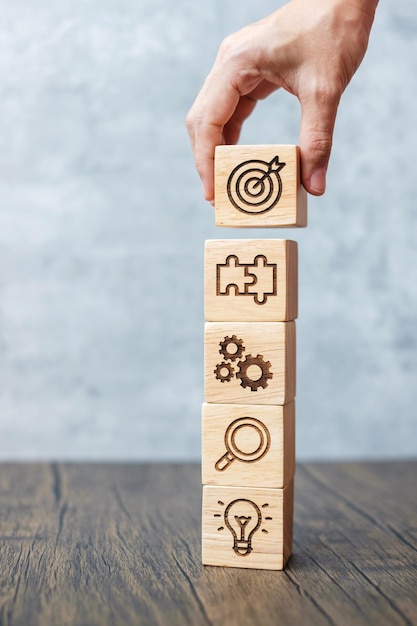 Foto bloque de madera de mano con estrategia de objetivo de negocio objetivo de acción de misión objetivo de investigación de trabajo en equipo y concepto de idea